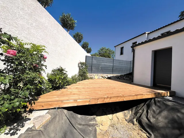 Terrasse en bois posée devant une maison, réalisée par Icamie Rénovation